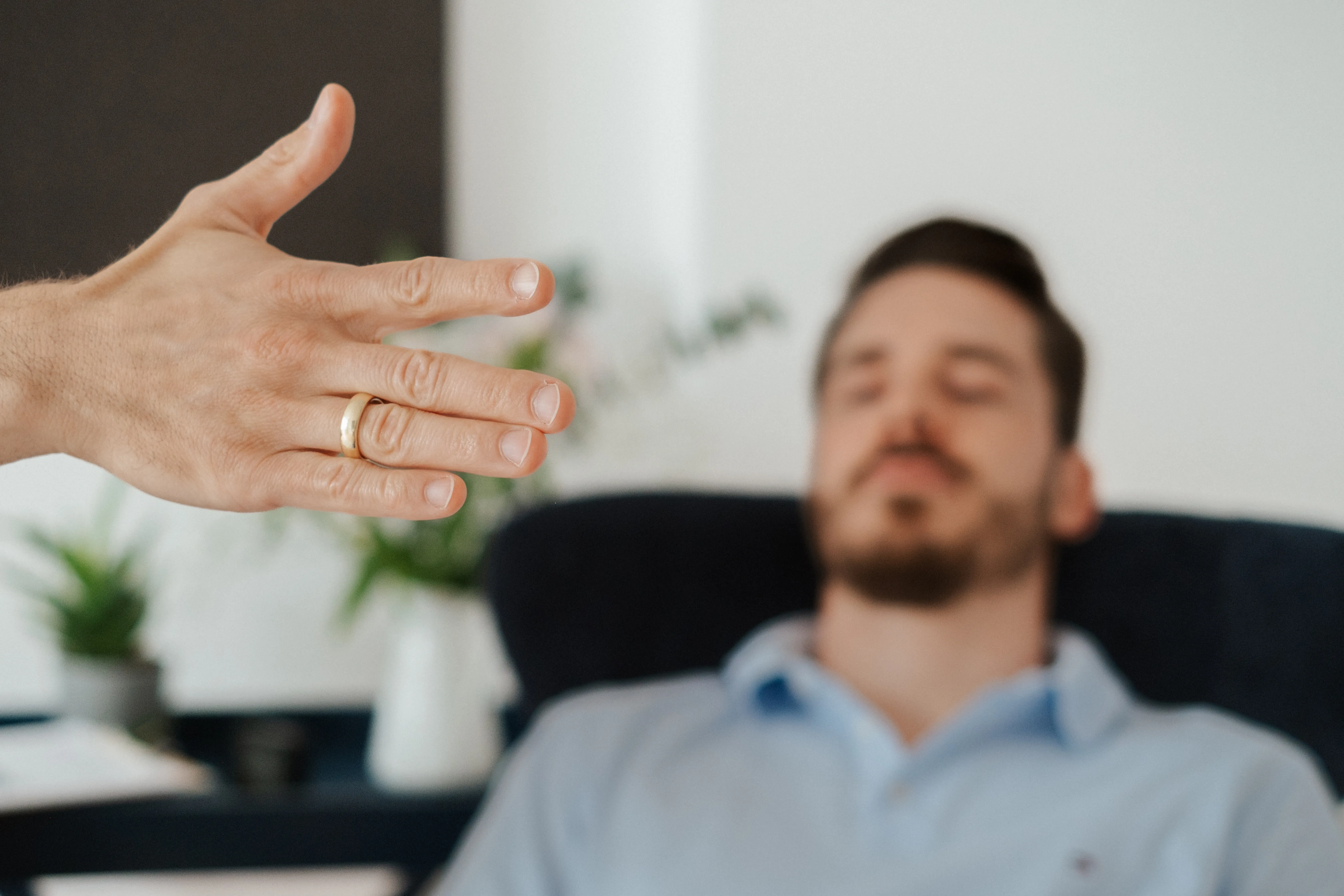 Eine Hand begleitet einen entspannten Klienten in einer Hypnosesitzung